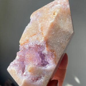 May include: A large, clear, amethyst crystal with a natural, rough exterior and a purple, crystalline interior. The crystal is shaped like a point and has a natural, raw look.