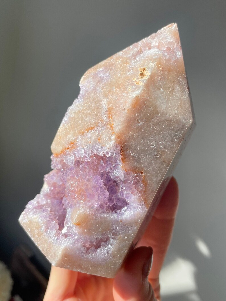 May include: A large, clear, amethyst crystal with a natural, rough exterior and a purple, crystalline interior. The crystal is shaped like a point and has a natural, raw look.