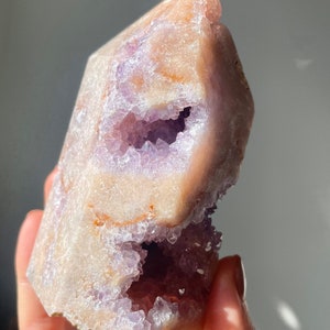 May include: A large, light purple amethyst crystal with a natural, hollowed-out center. The crystal has a pointed top and a rough, textured exterior.