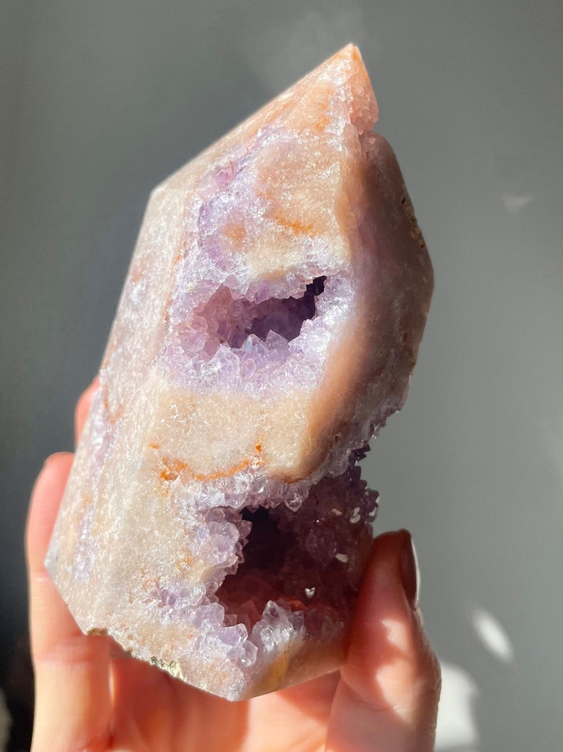 May include: A large, light purple amethyst crystal with a natural, hollowed-out center. The crystal has a pointed top and a rough, textured exterior.