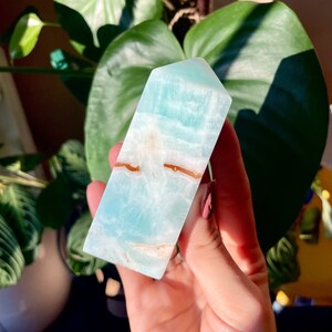 May include: A light blue and white crystal tower with brown veins. The tower is smooth and polished.