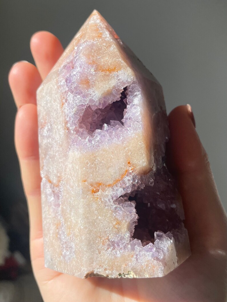 May include: A large, light purple amethyst crystal with a natural, hollowed-out center. The crystal has a pointed top and a flat base. The crystal is translucent and has a slight shimmer.