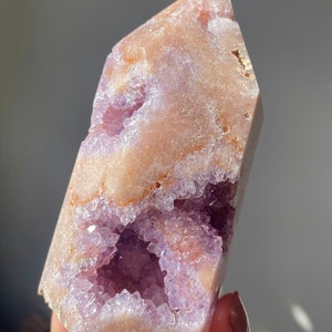 May include: A large, light purple amethyst crystal with a natural, raw, and rough texture. The crystal has a large, open cavity filled with smaller amethyst crystals. The crystal is a natural, raw, and rough specimen.