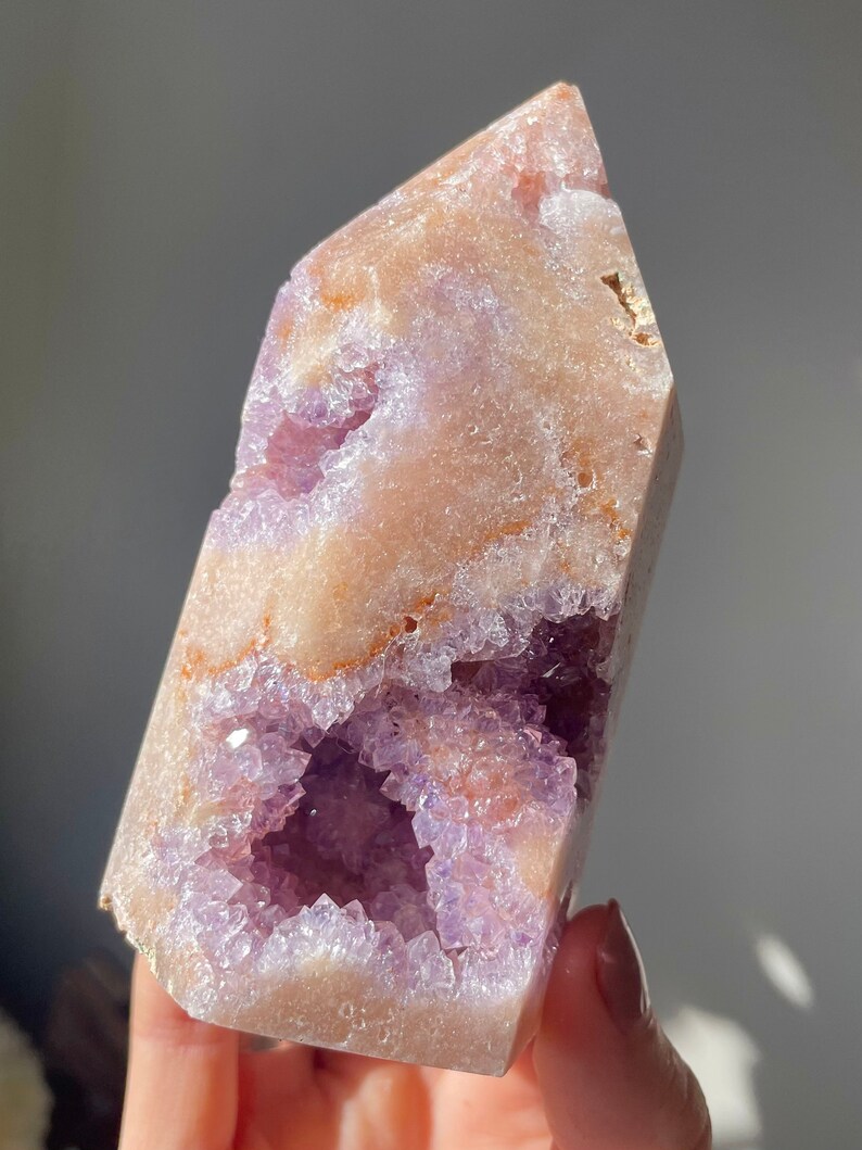 May include: A large, light purple amethyst crystal with a natural, raw, and rough texture. The crystal has a large, open cavity filled with smaller amethyst crystals. The crystal is a natural, raw, and rough specimen.