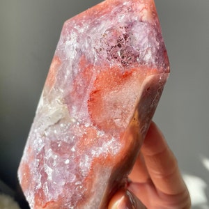 May include: A large, pink and white crystal point with a unique, swirling pattern. The crystal is translucent and has a smooth, polished surface.