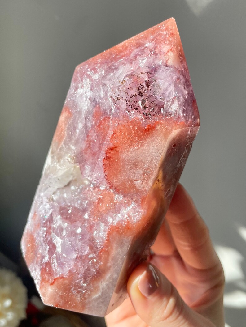May include: A large, pink and white crystal point with a unique, swirling pattern. The crystal is translucent and has a smooth, polished surface.