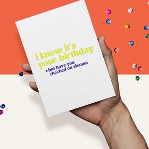 May include: A white card with the text "i know it's your birthday *but have you checked on sheana" in yellow and purple lettering.