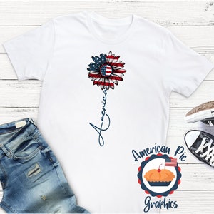 May include: White t-shirt with a red, white, and blue sunflower design and the word "America" written vertically down the stem. The design is from American Pie Graphics.