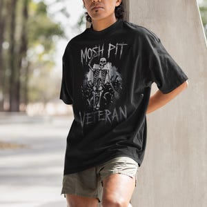 Unleash your rebel spirit with the Mosh Pit Veteran  Featuring a bold skeleton graphic, this edgy streetwear piece is perfect for punk rockers, skaters, and music lovers. Made from durable cotton, it's a must-have for non-conformists!