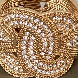 May include: A gold-toned bracelet with a knot design and clear rhinestones.
