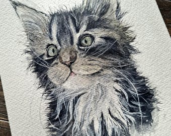 May include: Watercolor painting of a kitten with gray and black striped fur and green eyes. The kitten's fur is fluffy and detailed, with a soft, textured appearance. The artwork is on white paper, with a wooden background.