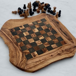 May include: A wooden chessboard with a natural wood finish and a checkered pattern. The board is made of olive wood and has a unique, irregular shape. The board is surrounded by black and brown chess pieces.