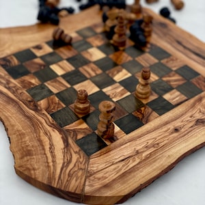 May include: A wooden chessboard with a natural wood finish and a checkered pattern. The board is made of olive wood and has a unique, rustic look. There are several chess pieces on the board, including pawns, rooks, and a bishop.
