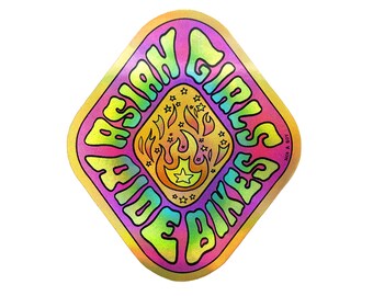 May include: A diamond-shaped sticker with a rainbow gradient background. The sticker features a stylized flame with stars and the text "Asian Girls Ride Bikes" in a rainbow gradient.