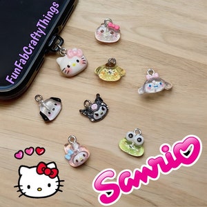 May include: A collection of colorful Sanrio character charms, including Hello Kitty, My Melody, Keroppi, and Badtz-Maru. The charms are made of clear resin with glitter accents and feature different Sanrio characters.