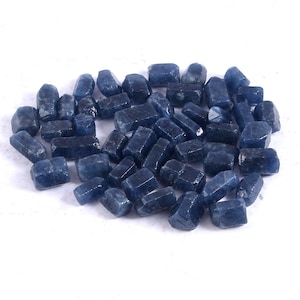 May include: A collection of raw, blue sapphire gemstones. The sapphires are in various sizes and shapes, with a rough, natural finish.