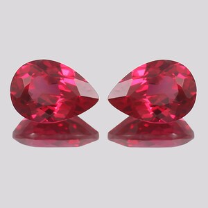 Könnte beinhalten: Zwei birnenförmige Rubingesteine, jeder mit einer tief roten Farbe und einem brillanten Schliff. Die Edelsteine ​​sind vor einem weißen Hintergrund platziert.