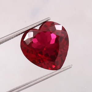 May include: A deep red heart-shaped gemstone with a faceted cut.