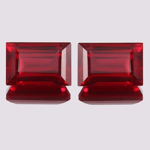 May include: Two red rectangular gemstones with a faceted cut.