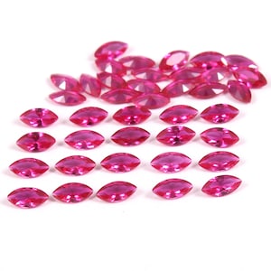 May include: A collection of 25 bright pink marquise-shaped gemstones. The gemstones are arranged in a staggered pattern on a white background.