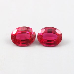 Könnte beinhalten: Zwei ovale, leuchtend rote Edelsteine. Die Edelsteine sind facettiert und hochglanzpoliert.
