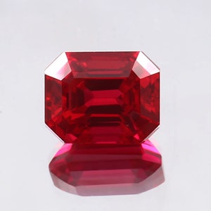 Puede incluir: Una piedra preciosa de color rojo intenso tallada en esmeralda con un alto pulido.