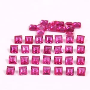 May include: A collection of square-cut, vibrant pink gemstones. The gemstones are arranged on a white surface, with some scattered and others neatly aligned. The facets of the stones catch the light, creating a sparkling effect. Ideal for jewelry making.