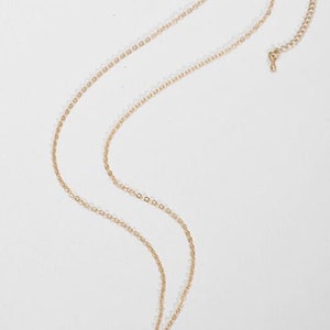 May include: A gold chain necklace with a round pendant featuring a turquoise stone.