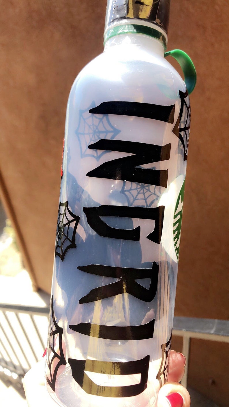 May include: A clear plastic water bottle with a black spiderweb design and the name "Ingrid" written in black lettering.
