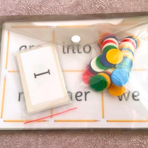 May include: A clear plastic pouch with a white card that says "I" on it. The pouch also contains a variety of colorful counters and two wooden sticks.