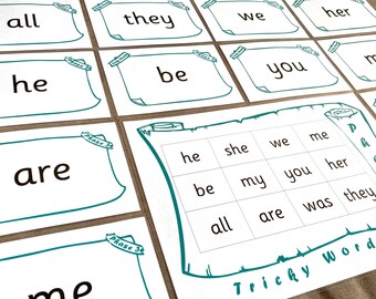 May include: A set of white cards with teal borders and text. The cards feature common sight words, including "all", "they", "we", "her", "he", "be", "you", "my", "are", "she", "me", "was", and "they". The cards are arranged in a grid pattern on a brown surface. The text "Tricky Words" is written in teal on a white background.