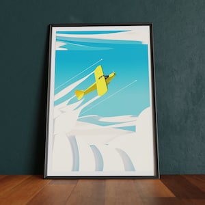 Puede incluir: Una impresión artística enmarcada que presenta un biplano amarillo volando por un cielo azul brillante con nubes blancas. La ilustración tiene un estilo retro, con el diseño del avión y las formas de las nubes. La obra de arte está enmarcada en un marco negro y se exhibe sobre una superficie de madera.