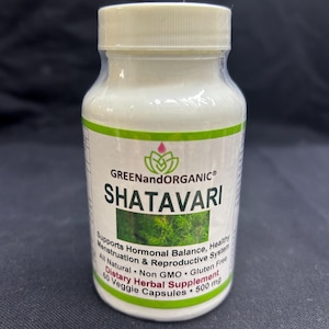 Puede incluir: Una botella de plástico blanco de suplemento herbal dietético "SHATAVARI" con una etiqueta verde y blanca. La etiqueta incluye texto sobre el equilibrio hormonal y la salud reproductiva. La botella contiene 60 cápsulas vegetales, 500 mg.
