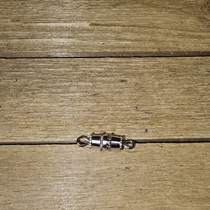 May include: Silver magnetic clasp for necklaces or bracelets. The clasp is made of metal and has a shiny finish.