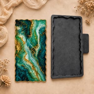 May include: A rectangular tray with a wavy edge featuring a marbled pattern in shades of deep teal, emerald green, and white with gold leaf accents, positioned next to a matching black silicone mould with a tab on the right side.