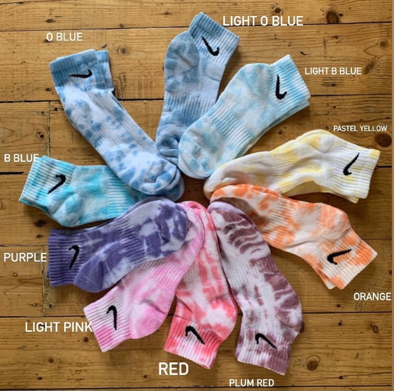 May include: A set of ten tie-dye socks with a Nike swoosh logo. The socks are in various colors, including light blue, blue, purple, light pink, red, orange, and yellow.