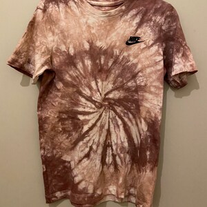 Op de afbeelding: Een bruin en wit tie-dye T-shirt met een zwart Nike-logo op de linkerborst.