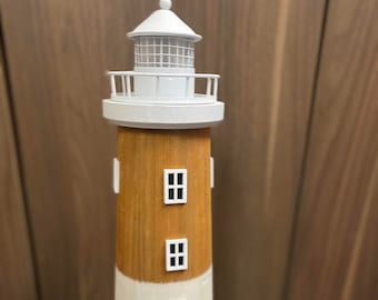 May include: A wooden lighthouse figurine with a white top and brown and white stripes. The lighthouse has three windows and a small door.