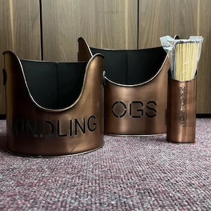 May include: Three copper-coloured metal containers for storing kindling, logs, and matches. The containers have black interiors and are labelled "Kindling", "Logs", and "Matches".