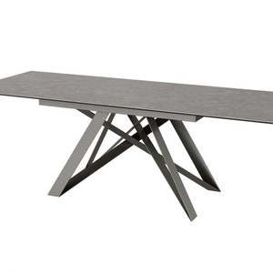 Puede incluir: Una mesa de comedor rectangular gris con una base de metal geométrica única. La superficie de la mesa está hecha de un material texturizado que se asemeja al concreto.