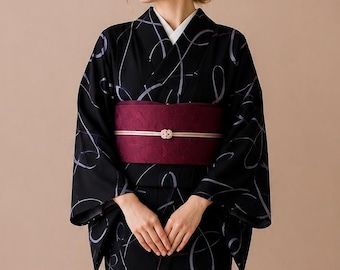 May include: A black kimono featuring a pattern of light gray swirling lines, paired with a wide, textured dark burgundy obi sash. The sash is secured with a thin, light-colored cord featuring a small, decorative, flower-shaped knot at the center.