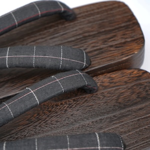 May include: A pair of dark brown wooden geta sandals with black and white checkered fabric straps.