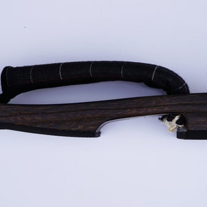 May include: A pair of dark brown wooden geta sandals with a black fabric strap. The sandals have a simple design and are made of natural materials.