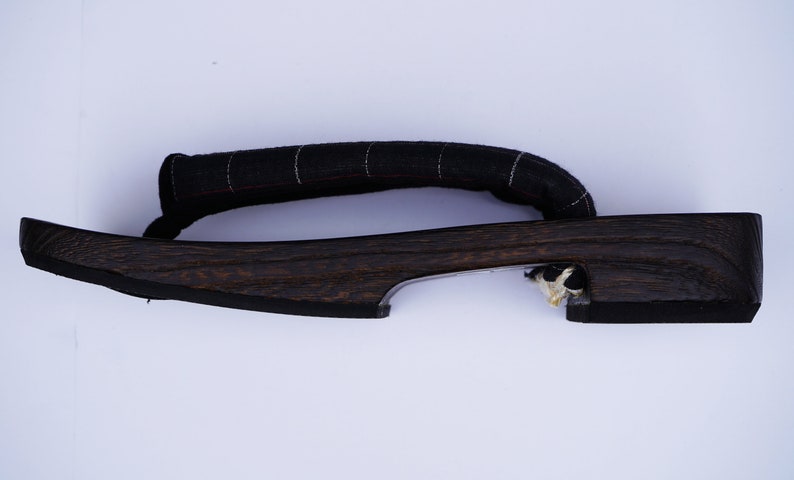May include: A pair of dark brown wooden geta sandals with a black fabric strap. The sandals have a simple design and are made of natural materials.