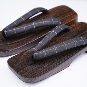 May include: A pair of dark brown wooden geta sandals with black and white checkered fabric straps.