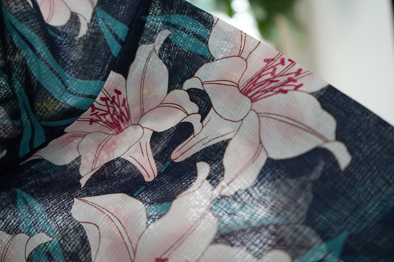 Puede incluir: Primer plano de una tela azul oscuro con un patr&oacute;n floral blanco y rosa. La tela tiene una superficie texturizada y las flores son lirios.