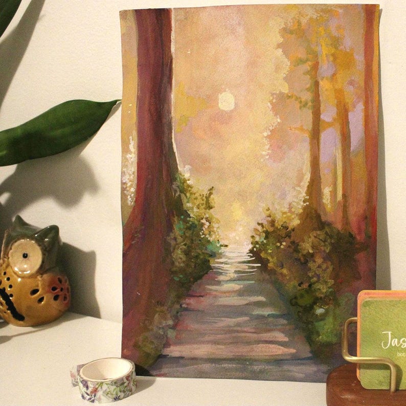 Op de afbeelding: Aquarel schilderij van een bospad dat leidt naar een helder, nevelig licht. Het pad wordt geflankeerd door bomen en weelderige groene struiken. Het kleurenpalet omvat warme tinten geel, oranje en bruin, waardoor een serene en uitnodigende sc&egrave;ne ontstaat.