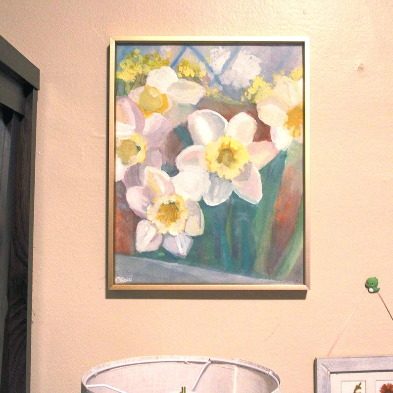 Puede incluir: Pintura enmarcada de narcisos. La obra presenta narcisos blancos y amarillos con tallos y hojas verdes. La pintura est&aacute; en un marco dorado y cuelga de una pared beige.