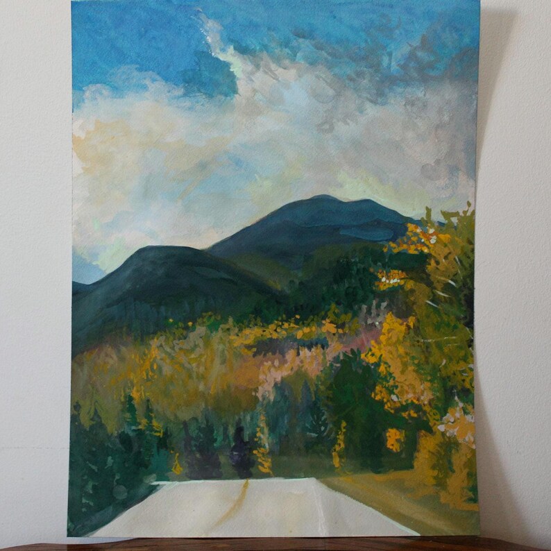 May include: An oil painting of a mountain landscape with a road in the foreground. The sky is blue with white clouds. The mountains are dark green, and the trees are a mix of green and yellow.