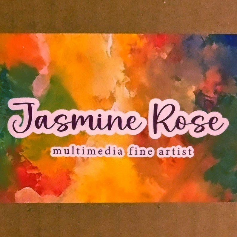 May include: A rectangular business card featuring a vibrant, abstract watercolor background with blended hues of orange, yellow, green, and blue. The text Jasmine Rose is printed in a dark purple script font, with multimedia fine artist below.